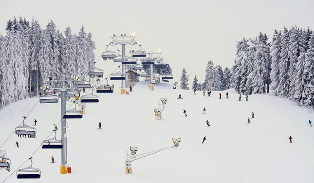 Wintersportler:innen auf schneebedeckter Skipiste mit Skilift in Winterberg 