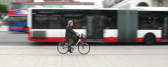 Fahrradfahrer fährt an einem Linienbus vorbei