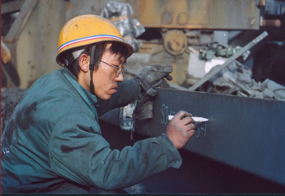 Ein chinesischer Arbeiter beschriftet eine Bauteil der Kokerei Kaiserstuhl. 