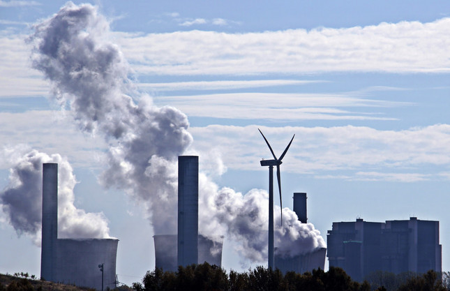 Windräder vor Kohlekraftwerk, Rauchwolken aus Kaminen bei Kohlekraftwerk zu sehen